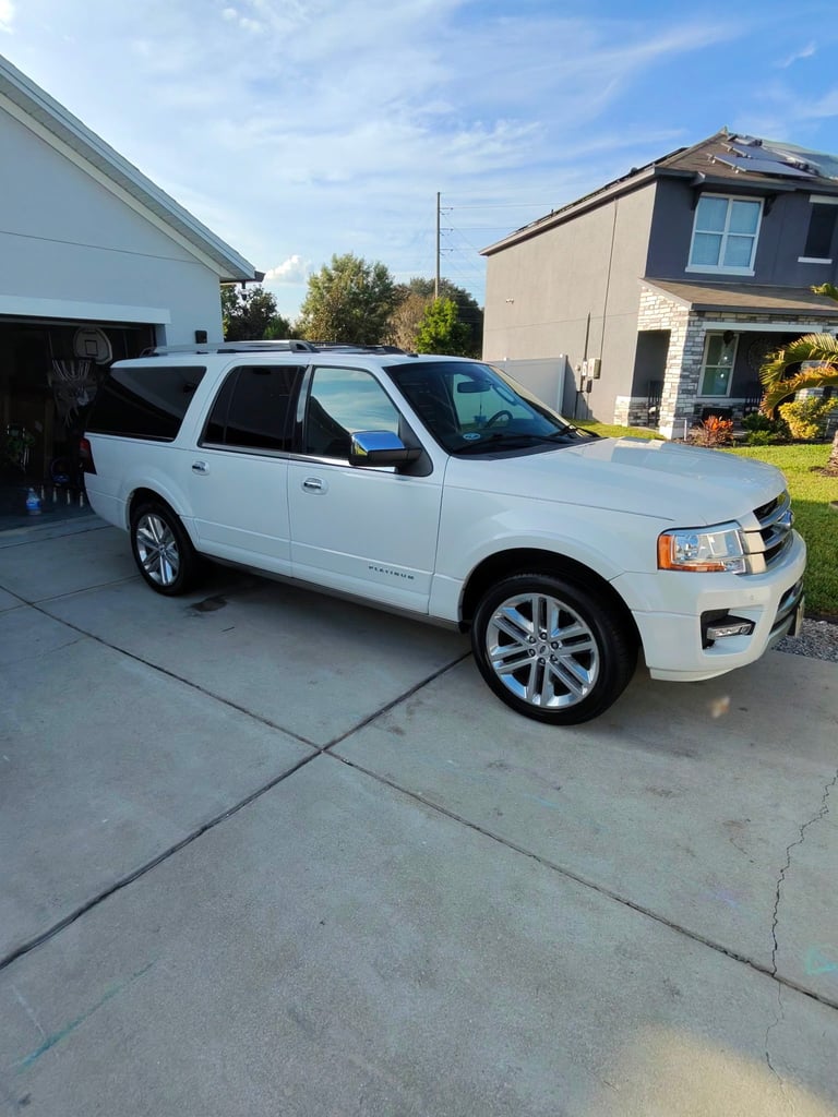 White Ford Expedition SUV parked in driveway in front of garage and residential homes