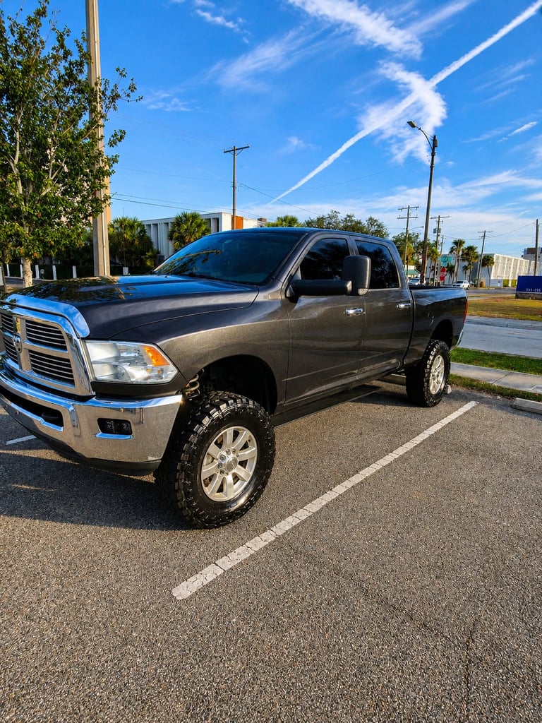 Gray and blue Dodge Ram pickup truck parked in a lot on a sunny day with clear blue sky