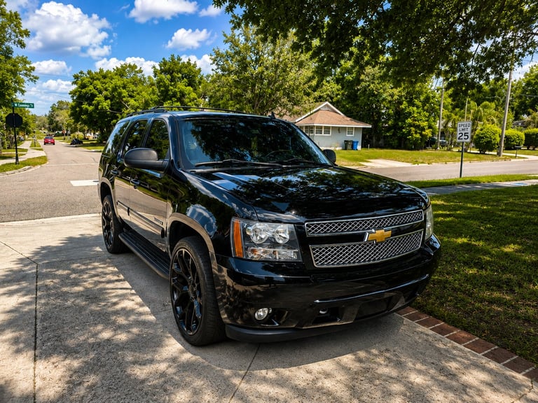 Black Chevrolet Tahoe SUV parked on residential street with trees and houses in background