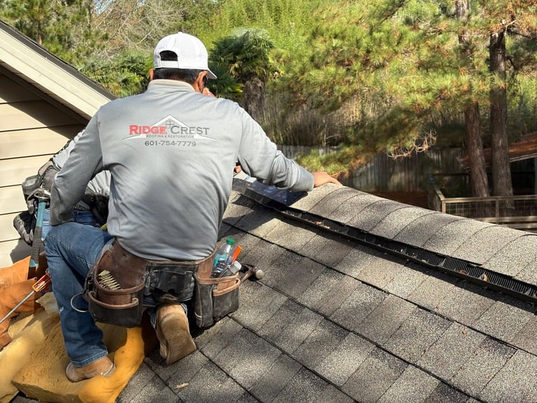 RidgeCrest roofer in white hard hat installing roof ridge vent on asphalt shingle roof