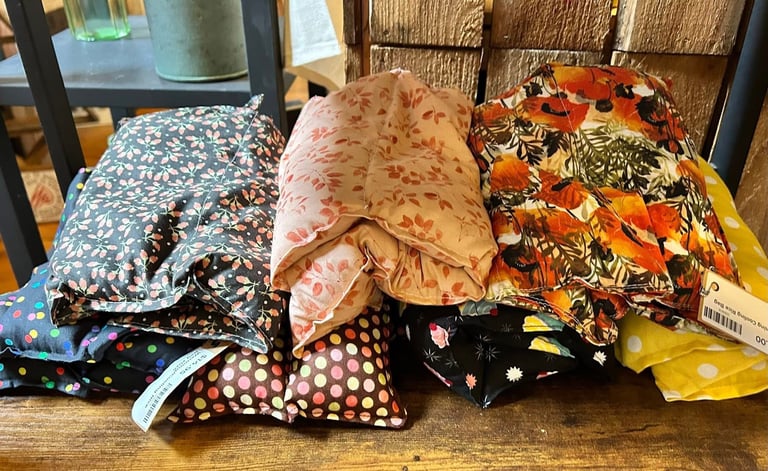 Folded fabrics and textiles with various patterns displayed on a wooden table in a retail setting