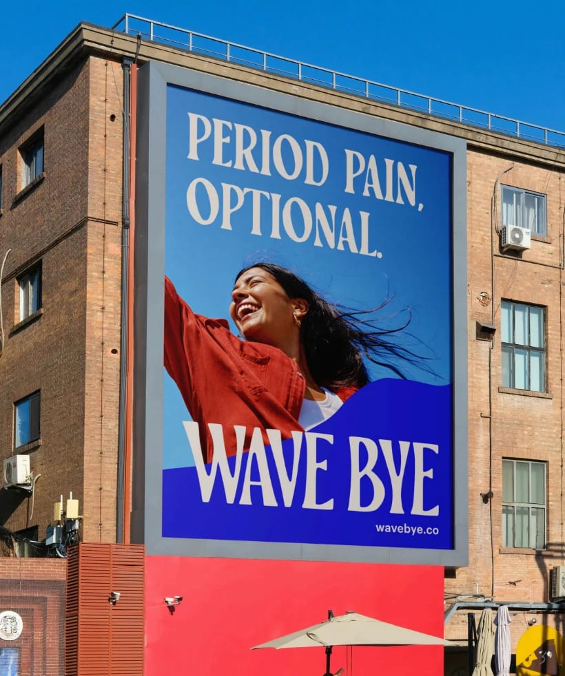 Billboard advertisement on brick building showing smiling woman in red shirt with text Period Pain, Optional and Wave Bye