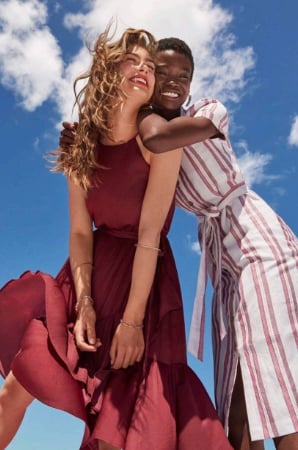 Couple embracing outdoors against a blue sky, both faces visible and laughing together
