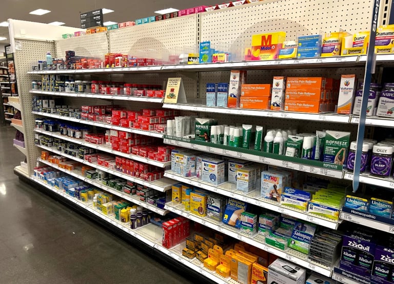Retail store display shelf stocked with colorful boxes of health and beauty products organized by color and category