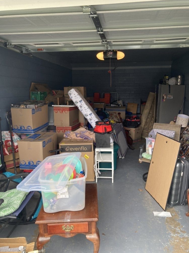 Garage filled with boxes, bins, and furniture before a JC'S Hauling cleanout