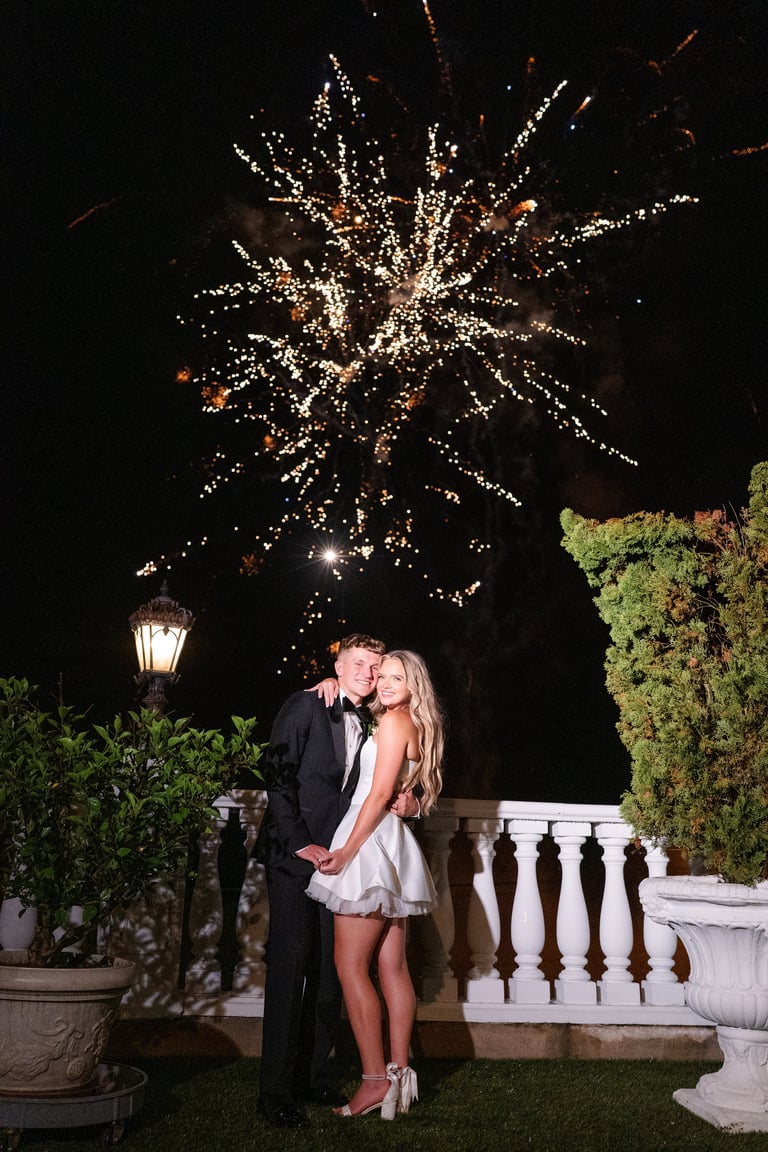Couple kissing on a garden terrace with golden fireworks bursting overhead at night