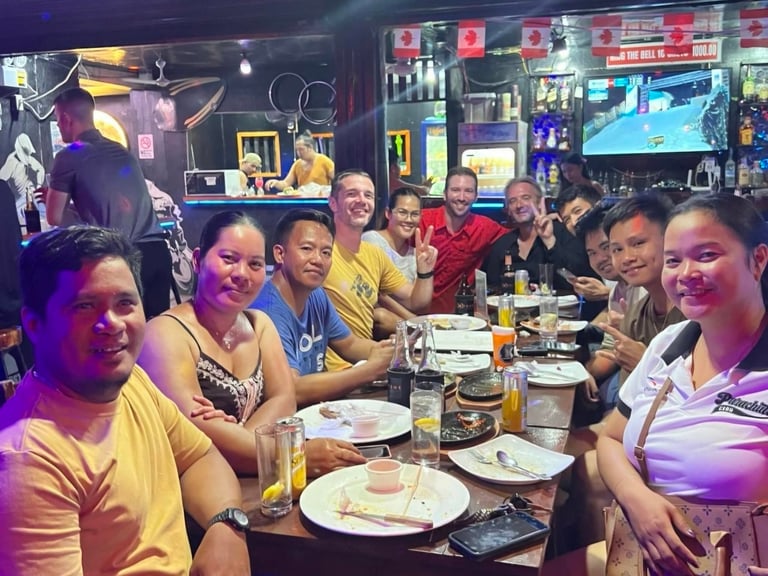 Group of people enjoying dinner and drinks together at a restaurant bar with food plates and drinks on the table