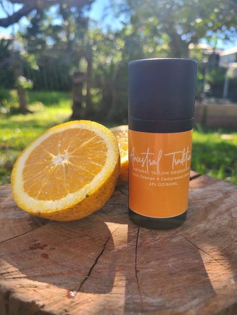 Orange and cedarwood natural tallow deodorant with fresh orange slice next to it