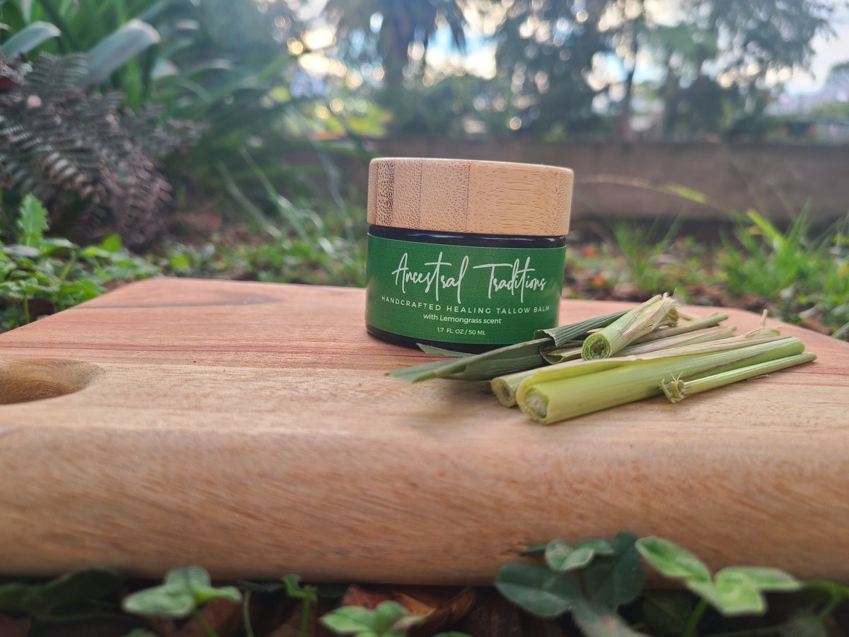 Jar of Armpit Toothpaste on wooden log with fresh lemongrass stalks in a garden setting