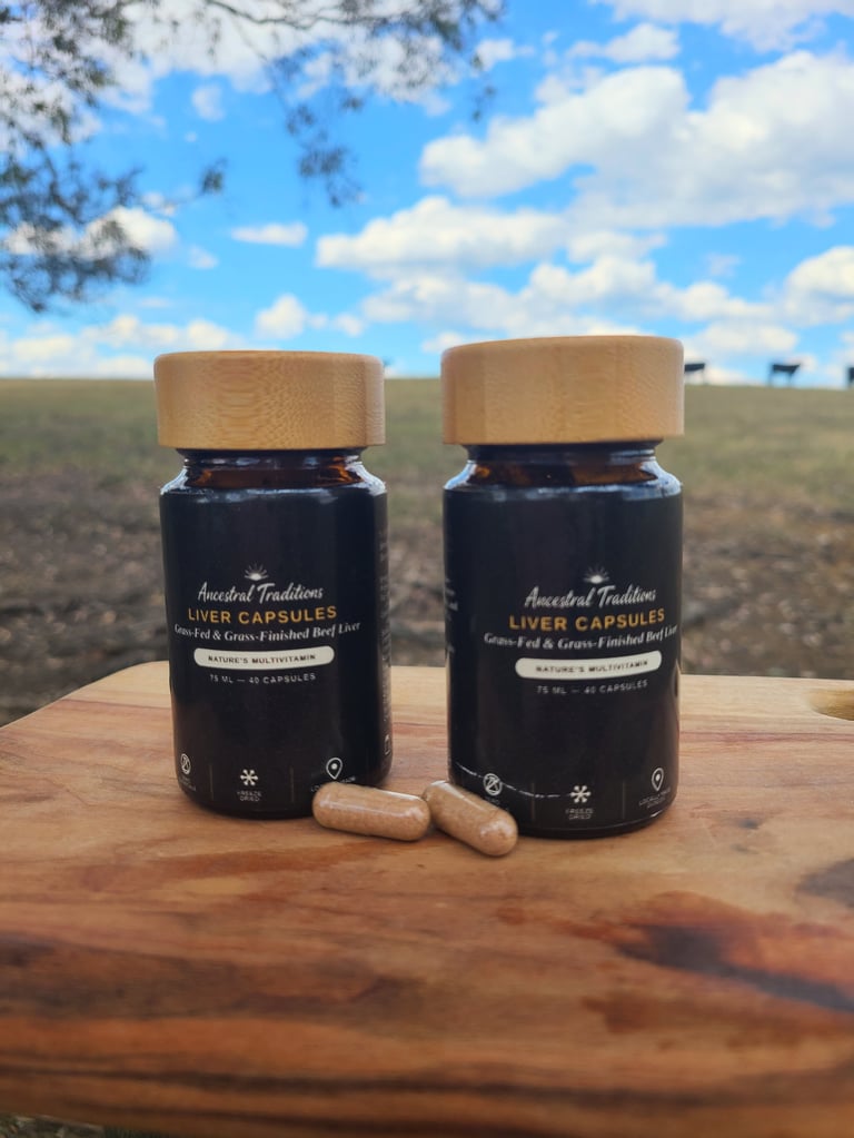 Two dark glass bottles of Ancestral Traditions liver capsules with wooden caps on a wooden table, rural landscape background