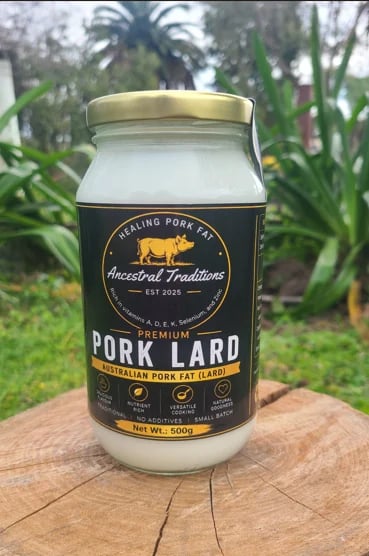 Jar of Ancestral Traditions Premium Pork Lard on wooden surface with garden foliage in background
