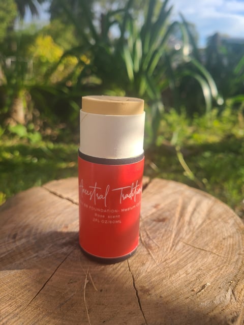 Red Ancestral Traditions Tallow BB Foundation Medium tube with white cap and beige top on a wooden surface with green foliage and mountains in background