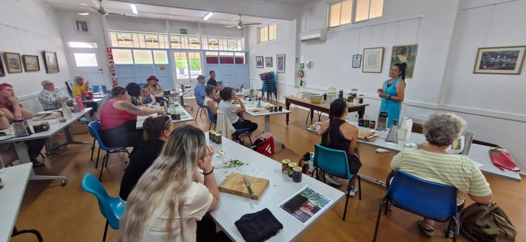 A classroom filled with students seated at wooden tables with art supplies and papers, engaged in a workshop activity