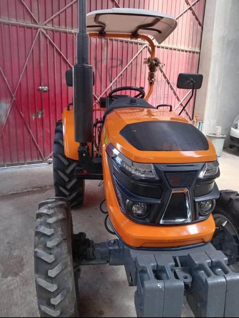 Orange and black ride-on lawn mower with canopy parked in a warehouse with red corrugated metal walls
