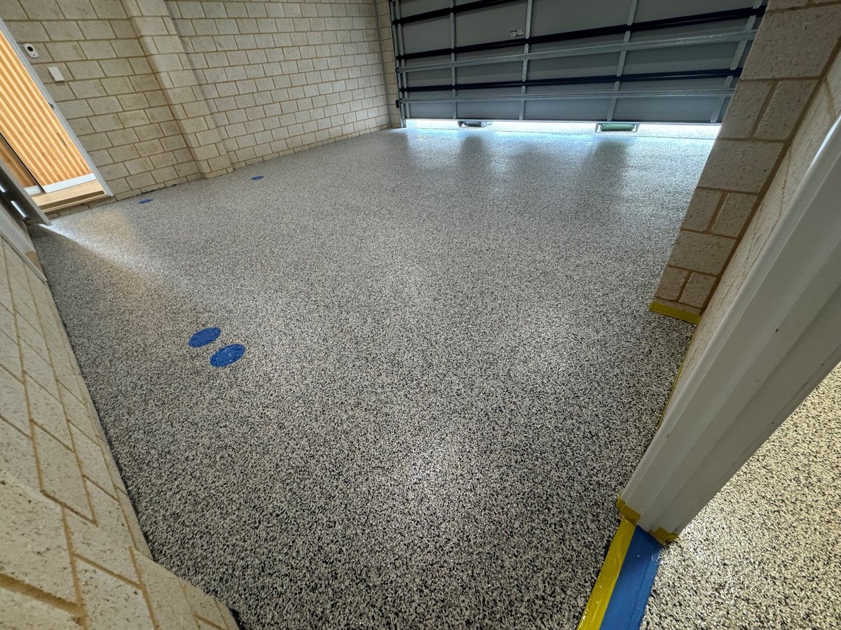 Empty garage interior with a fresh grey speckled flake epoxy floor and white walls