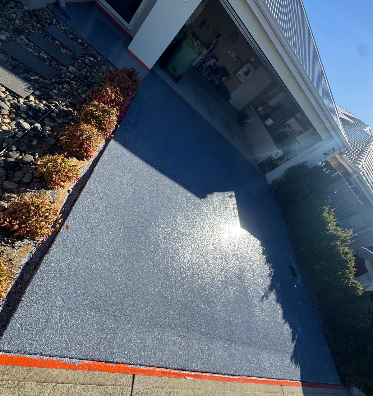 Modern driveway with a blue-grey speckled flake epoxy finish beside a frosted glass entry