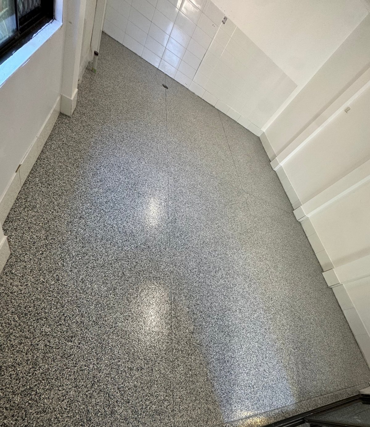 Bathroom with a fresh light grey speckled flake floor and white tiled shower
