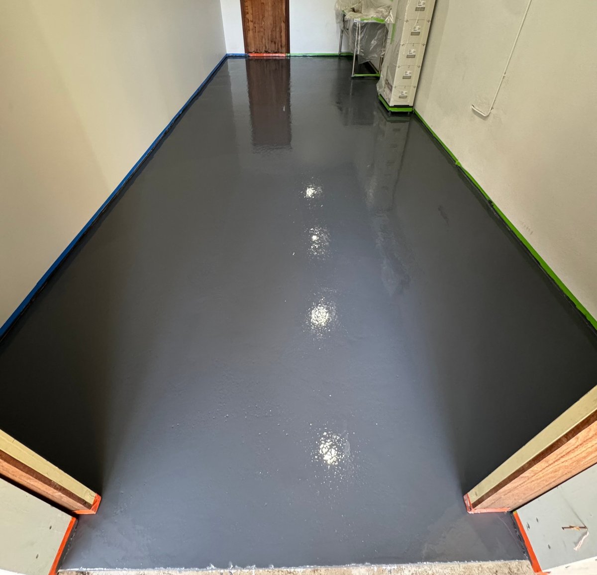 Empty hallway with a fresh dark grey gloss epoxy floor and coloured edge trim