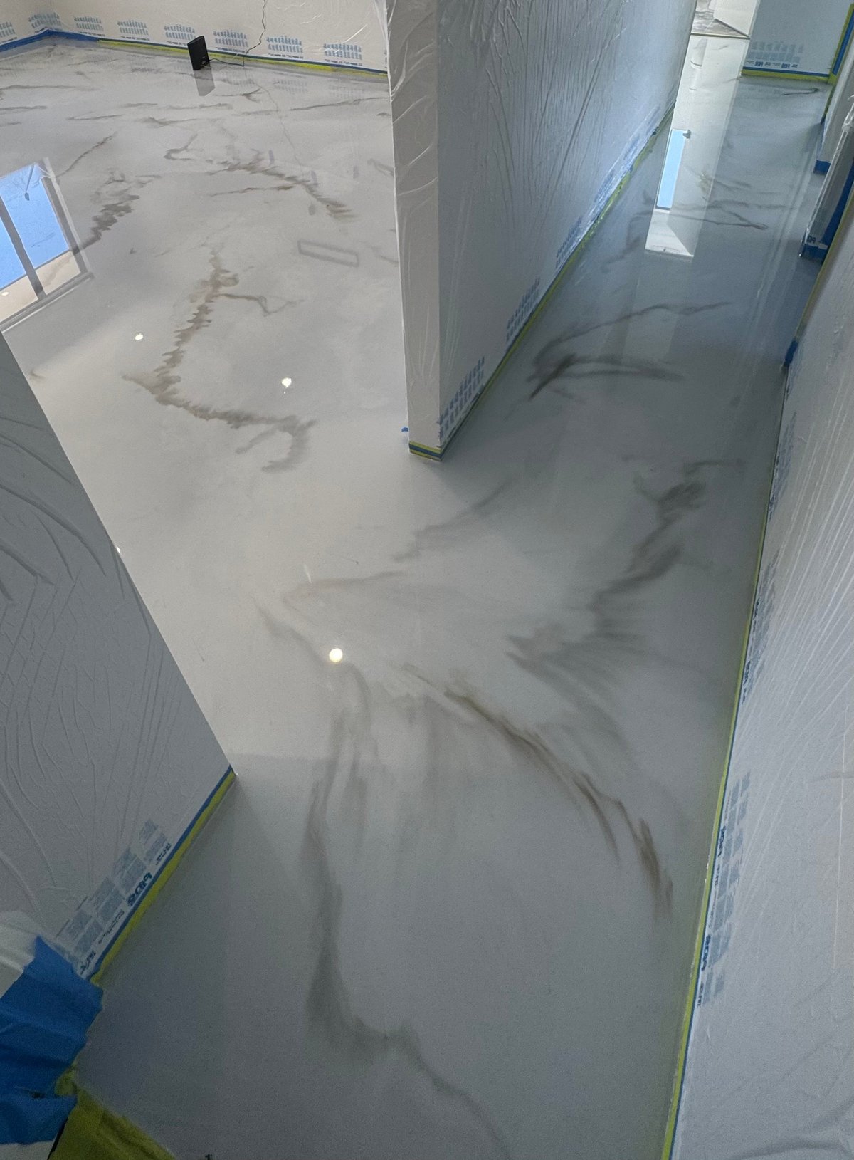 Concrete floor with dark staining and streaks in a hallway under preparation for epoxy