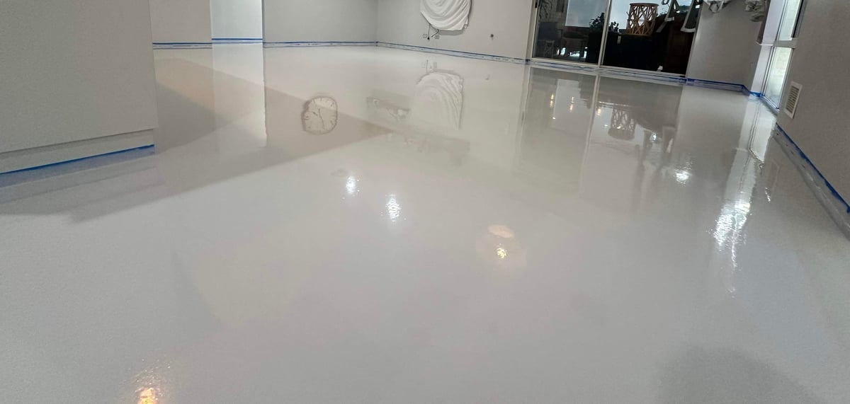 Empty warehouse with a mirror-finish white epoxy floor and blue edge masking
