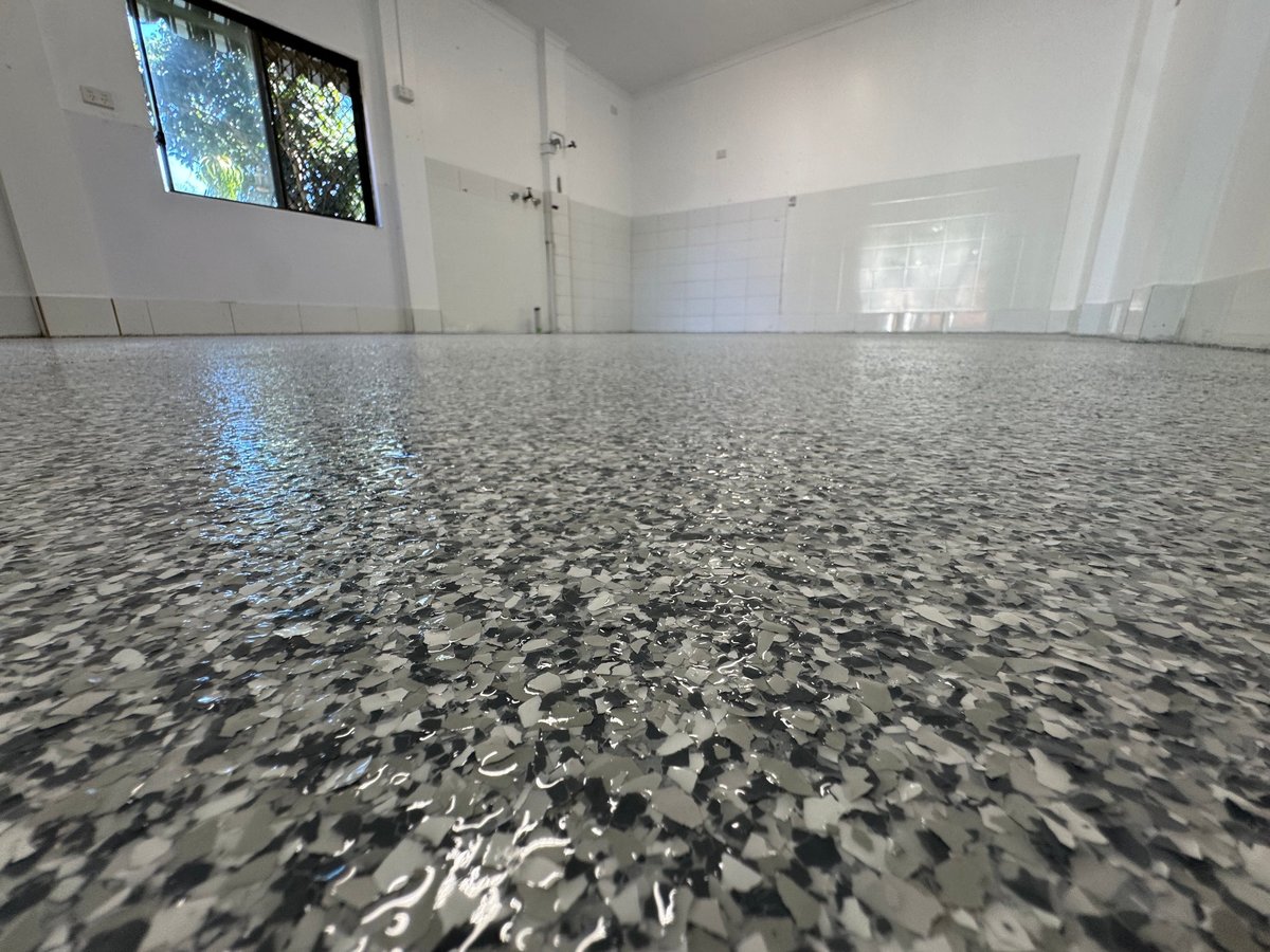 Modern bathroom with a polished speckled grey flake floor, white walls and glass shower