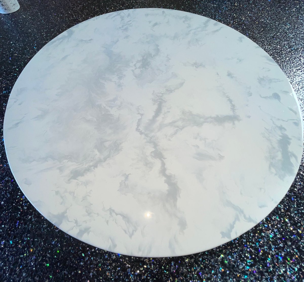 Round white marble-effect lazy susan on a dark speckled floor