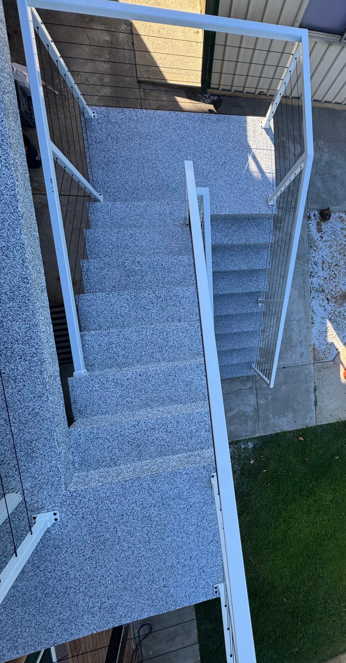 Staircase landing with a light grey speckled flake epoxy floor and white balustrade