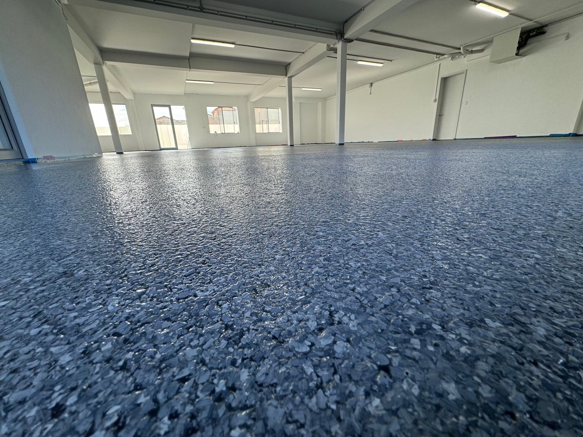 Large empty warehouse with a blue speckled flake epoxy floor and clean white walls
