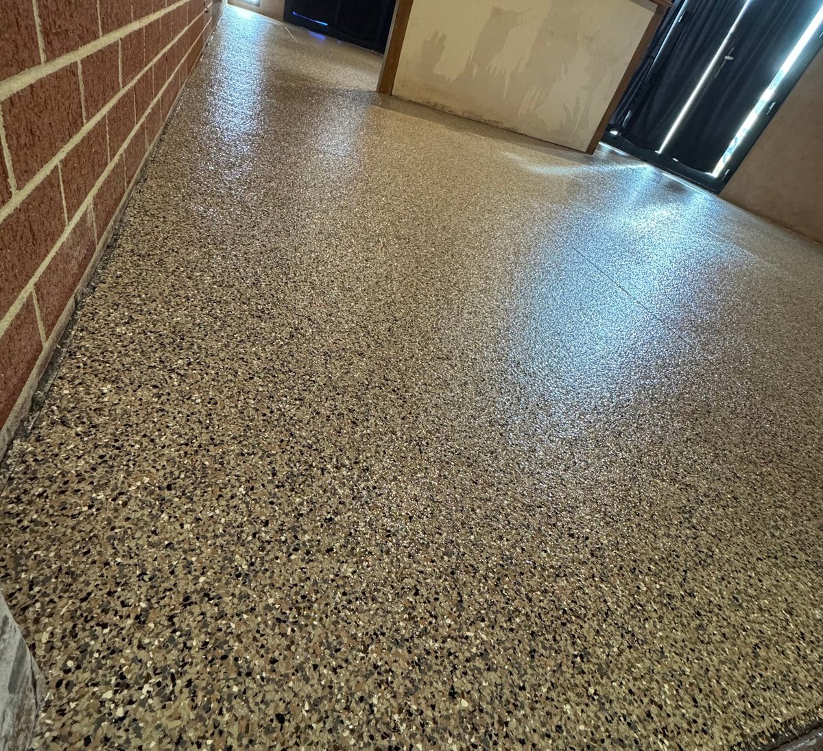 Glossy grey speckled flake floor inside a brick-walled interior space