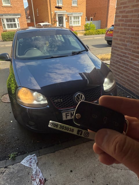 Dark blue VW Golf GTI Mk6 parked on a residential street in Scarborough. A new VW remote key is held up in the foreground on a green Scarborough Auto Locksmith lanyard.