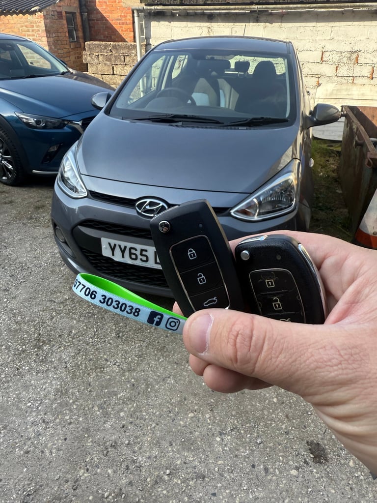 Person holding car keys in front of a silver Hyundai i10 parked in a lot