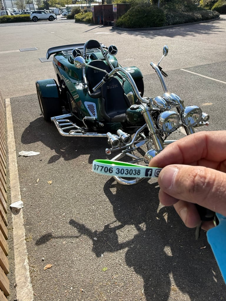 Hand holding a parking ticket in front of a blue and black motorcycle trike parked in a lot