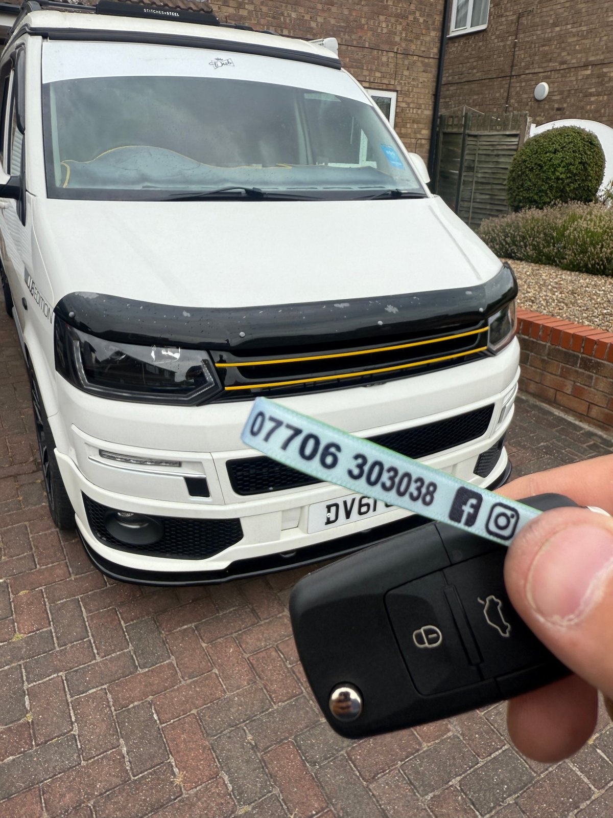 White VW Transporter T6 LWB on a brick driveway in Scarborough. A new VW remote key is held in the foreground on a green Scarborough Auto Locksmith lanyard, showing the phone number 07706 303038 and social media icons.