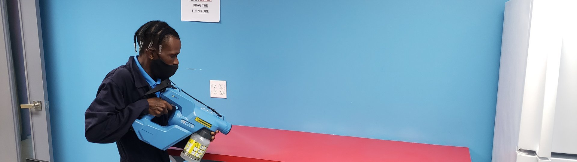 Man in dark jacket working on blue wall with tools near red surface
