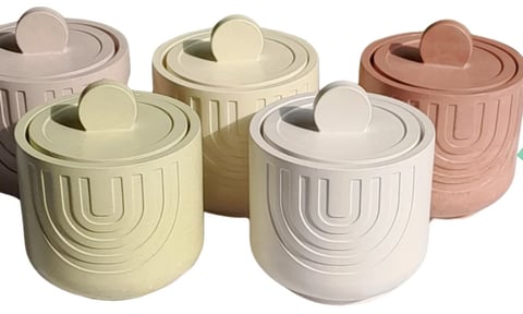 Five pastel-colored ceramic containers with lids in beige, cream, white, and terracotta featuring geometric arc patterns