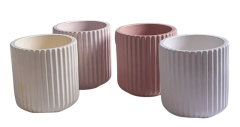 Four cylindrical ribbed planters in cream, mauve, burgundy, and gray arranged in a row.