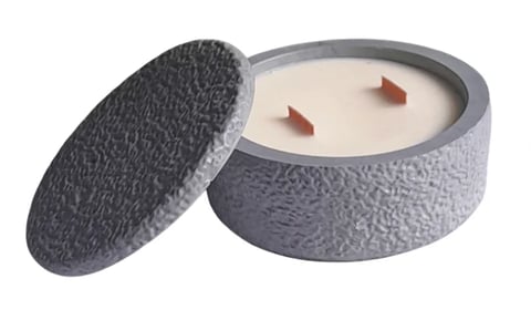 Gray textured candle jar with lid open, showing cream-colored candle with two red wicks inside