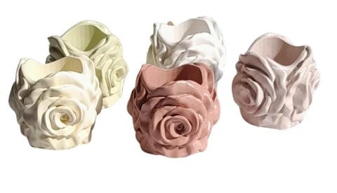 Three decorative ceramic or stone rose planters in cream, white, pink, and mauve tones