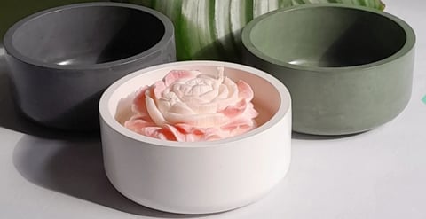Three decorative cylindrical boxes with pale pink rose inside the white box in front, flanked by empty black and sage green boxes