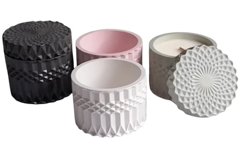 Four decorative candles in cylindrical jars with geometric textured lids in black, pink, white, and gray colors