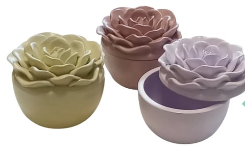 Three decorative flower-shaped ceramic planters in pale yellow, rose brown, and lavender with small pots for succulents