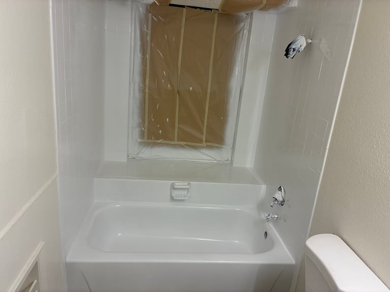 White bathroom with a refinished bathtub and shower enclosure with gold shower door