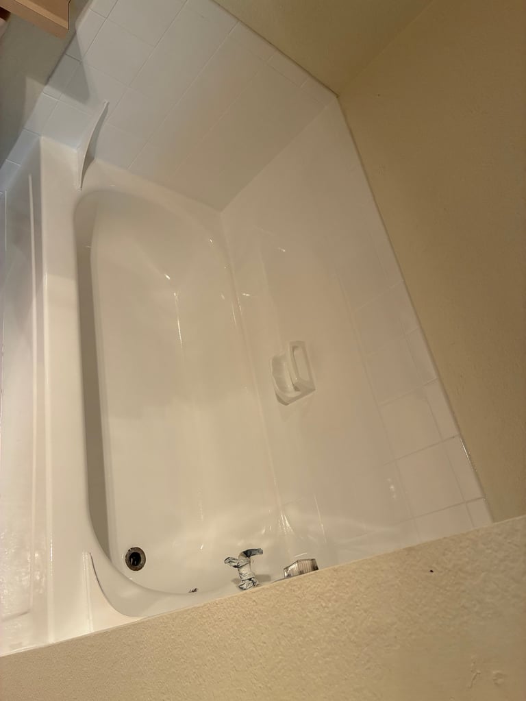 Empty white bathtub with chrome faucet and fixtures viewed from above after resurfacing