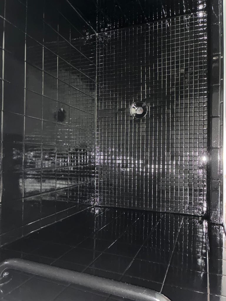 Modern black tile shower enclosure with metallic mosaic wall accents after resurfacing