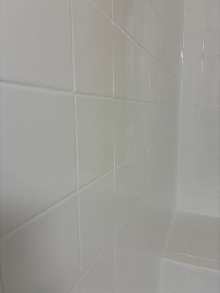 Close-up of freshly refinished white subway tile wall with clean grout lines and corner junction