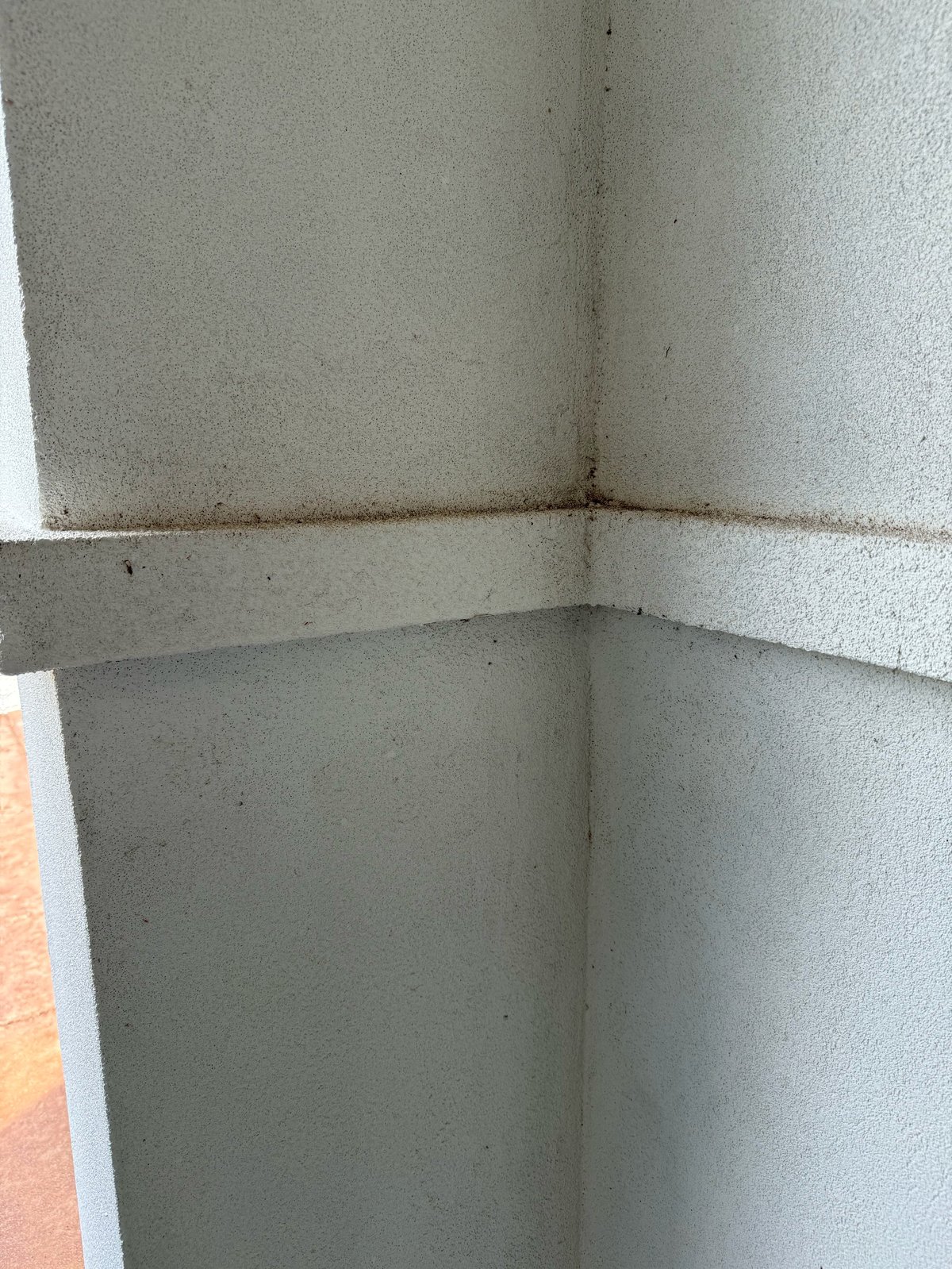 Before: interior corner of concrete walls with visible joint seams and moisture stains