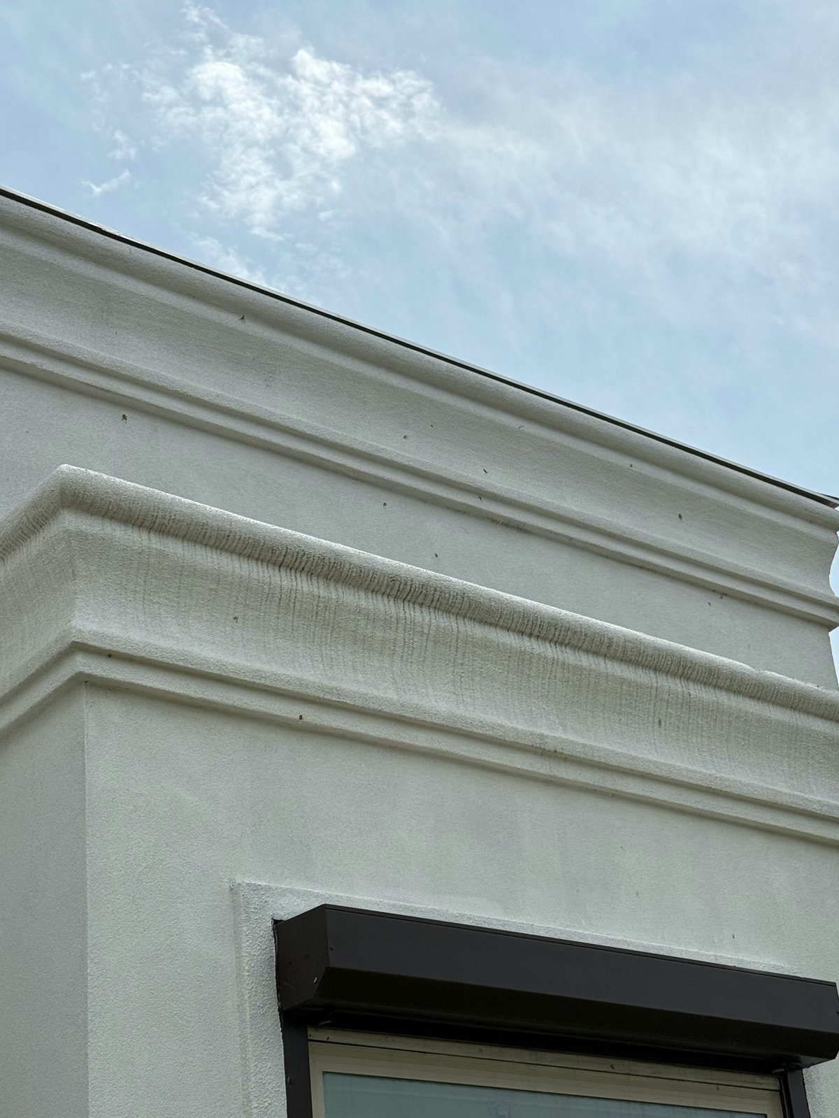 Before: modern building corner with white trim and molding against blue sky