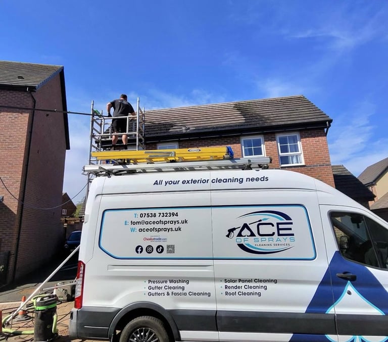 Worker on lift platform of ACE exterior cleaning van performing high-level building maintenance on brick house