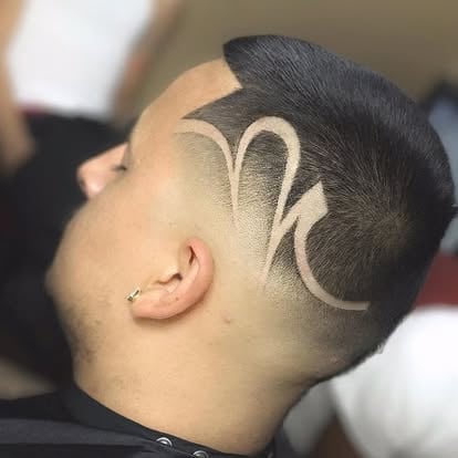 Side profile of a mans head showing a decorative line art tattoo design on his scalp and shaved head