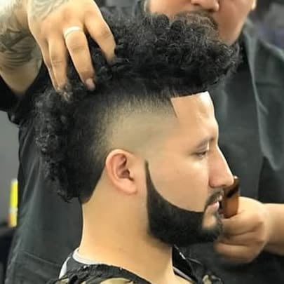 Barber styling clients curly textured hair and beard during a haircut at a salon